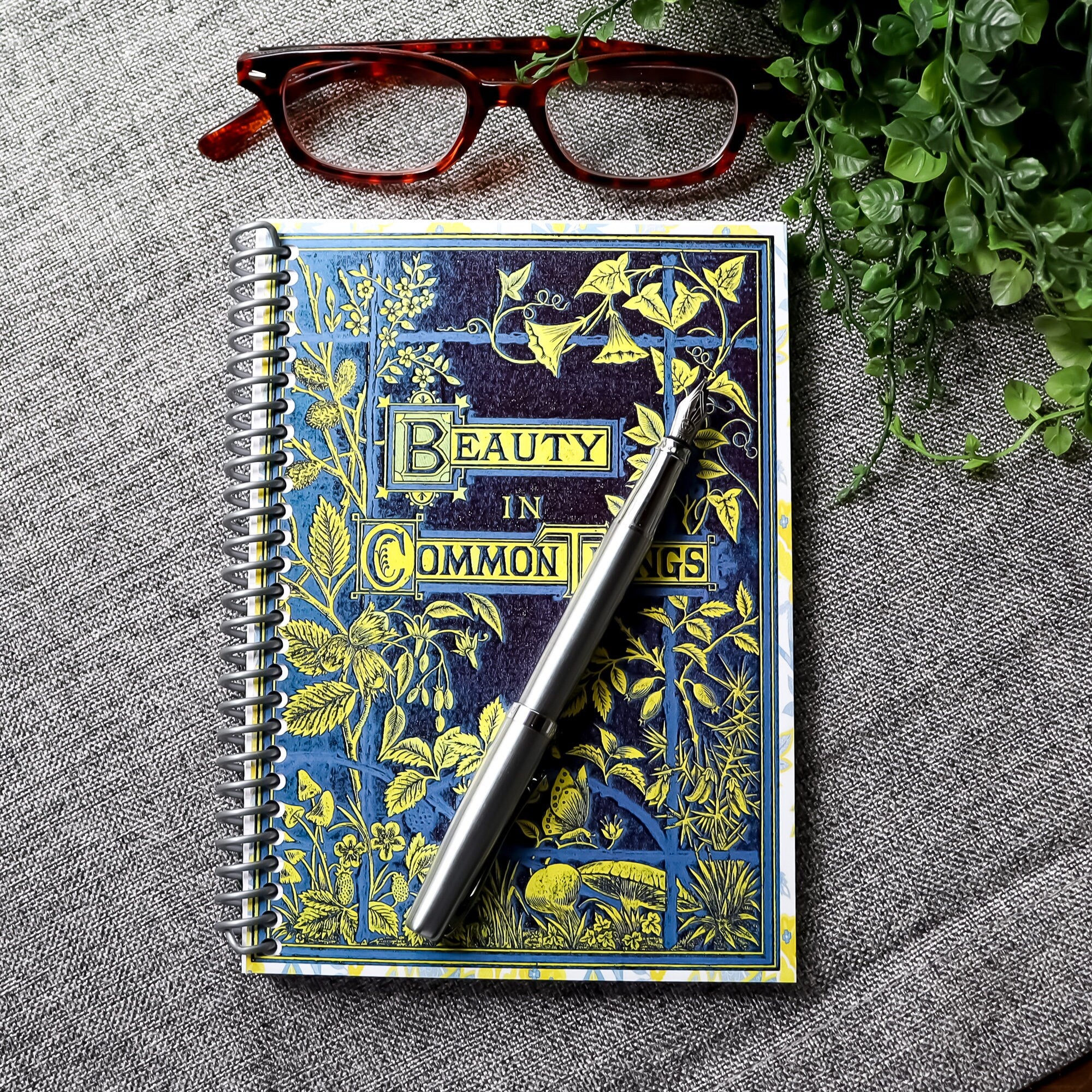 handmade travel notebook (5&quot; x 7&quot;) featuring a vintage book cover, Beauty in Common Things. Colors: navy blue, yellow, white, and light blue. Floral Patterns.