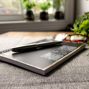 A travel-sized spiral notebook featuring a vintage book cover: FromDay To Day. Features a bold floral design. The colors are black, silver, gold and brown.